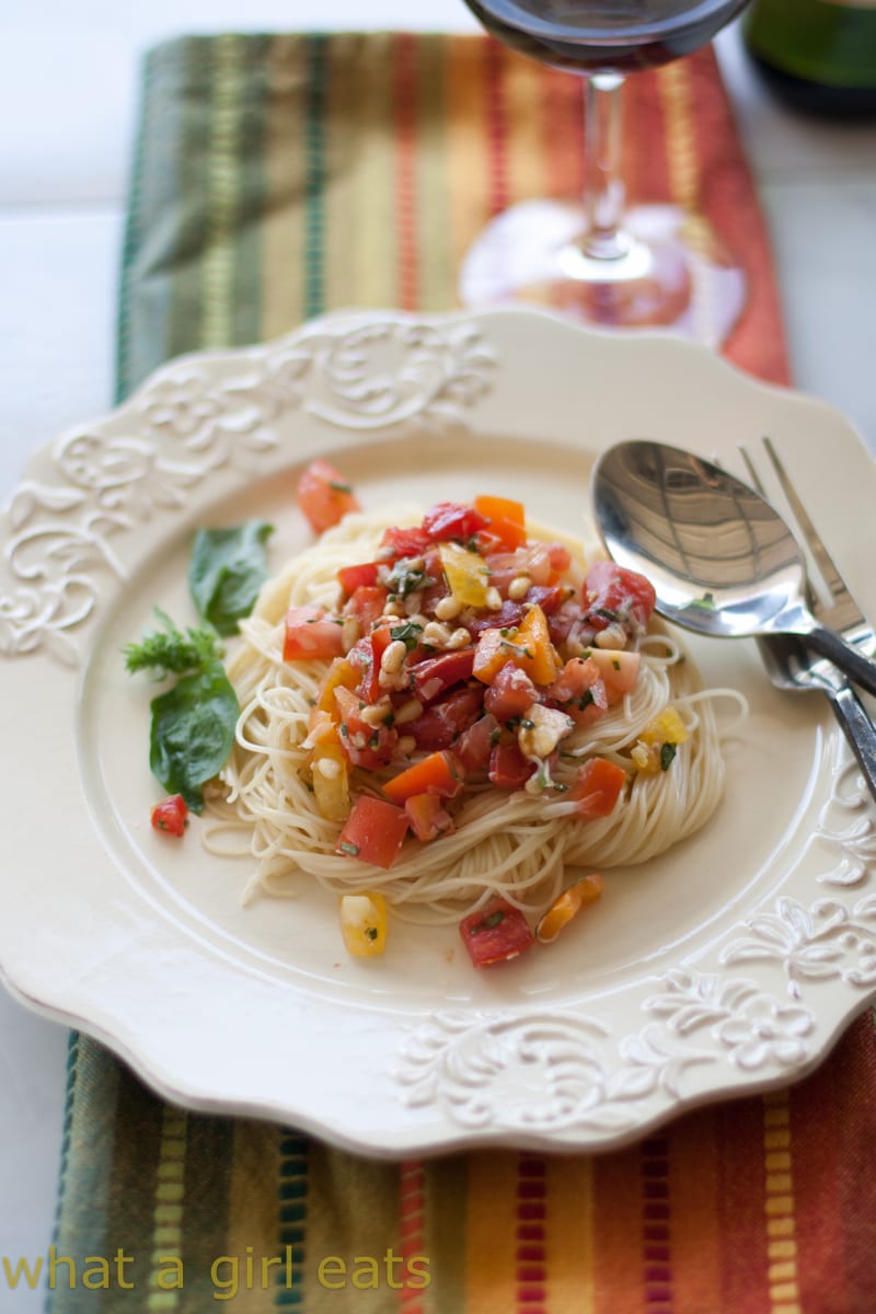No-cook summer pasta sauce over angel hair pasta on a pretty white plate.
