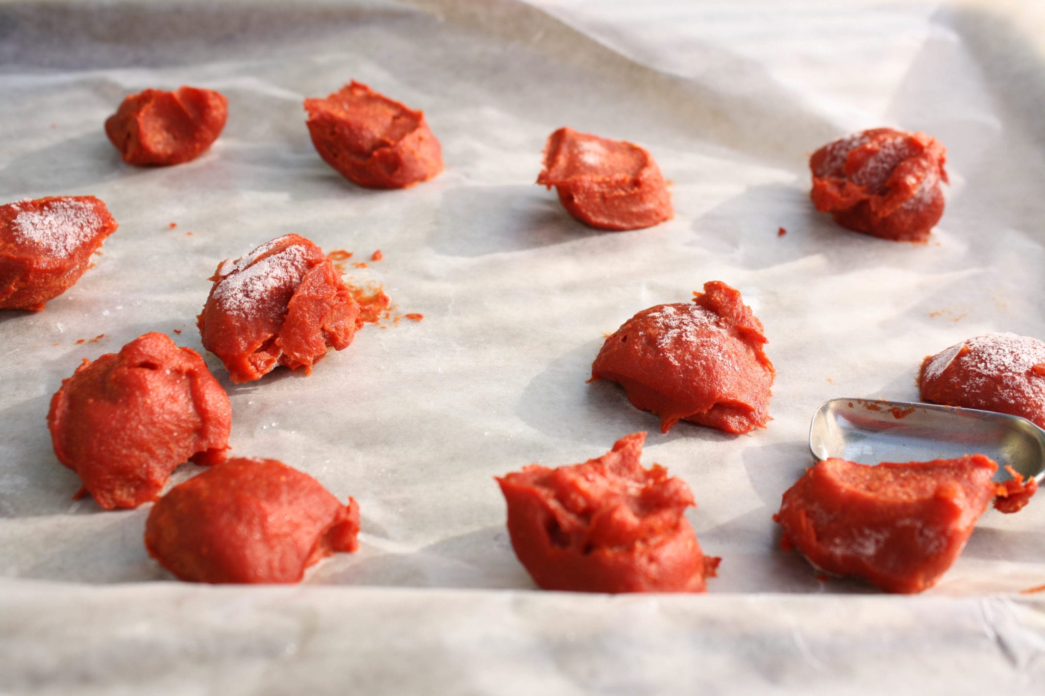 Frozen spoonfuls of tomato paste on parchment paper.