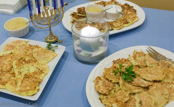 Potato latkes on serving platters on a table set for Hanukkah.