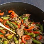 Szechuan beef is a popular, spicy Asian entree that's quick and easy to make. This recipe version is accented with sweet bell peppers and fresh asparagus. | Recipe from @whatagirleats