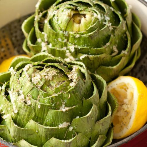 Artichokes ready for steaming with lemon, Italian herbs, kosher salt and olive oil.