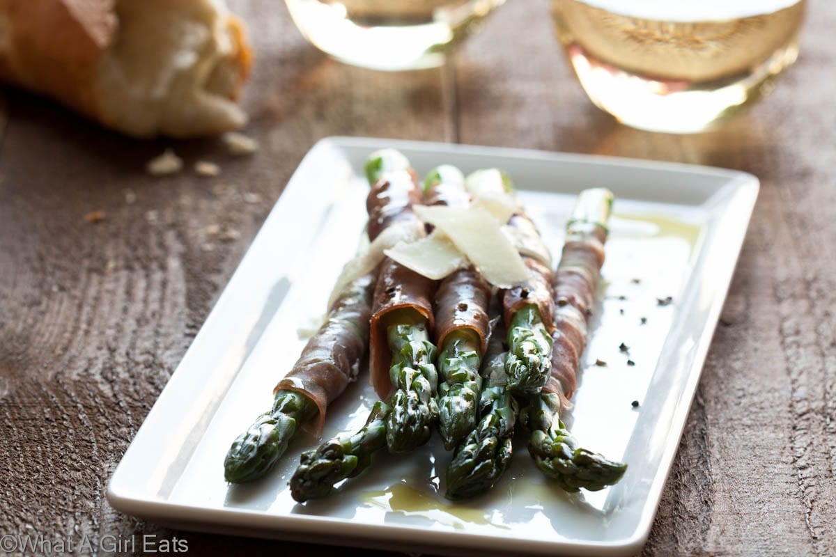 Prosciutto wrapped asparagus is a delicious, easy to make appetizer or side dish recipe. Tender spring asparagus is wrapped with salty prosciutto and shaved Parmesan cheese. | WhatAGirlEats.com