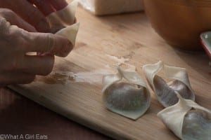 How to make wontons. Fold the edges of the wontons together.
