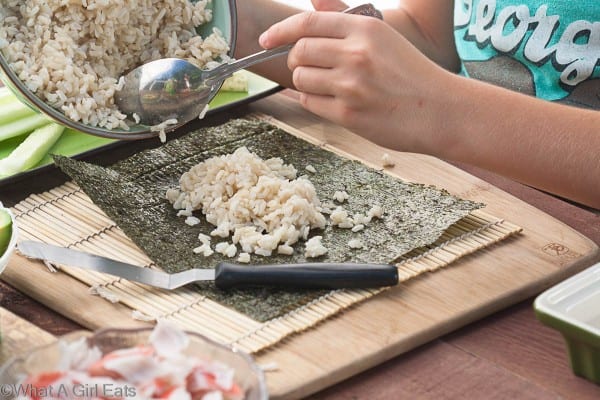 Spreading rice onto a piece of nori, (seaweed).