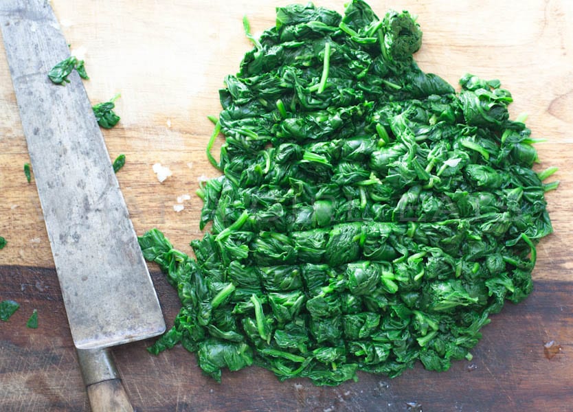 Chopped spinach and knife on a cutting board.