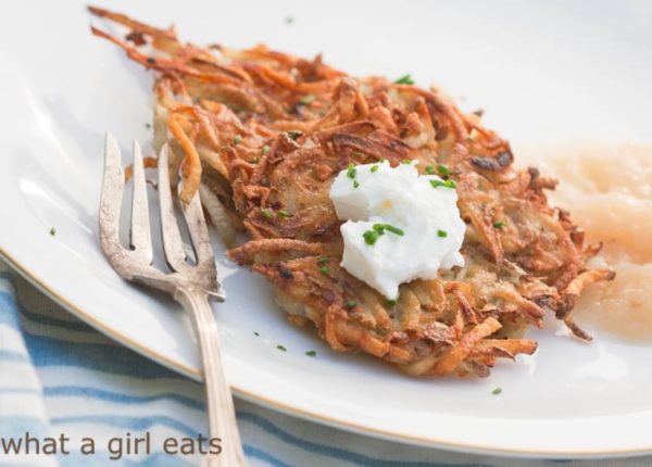 Crispy potato pancake on a plate with sour cream and applesauce. 
