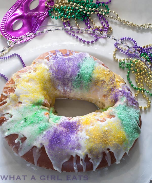 King Cake dessert on a plate with Mardi Gras beads around it.