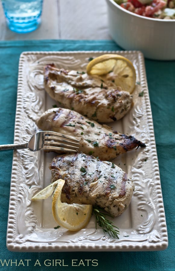 Grilled chicken with lemon and herbs on a serving plate.