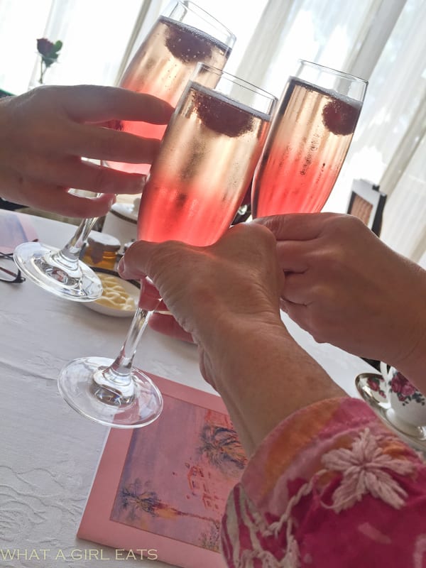 Three hands toasting with Kir Royale cocktails.