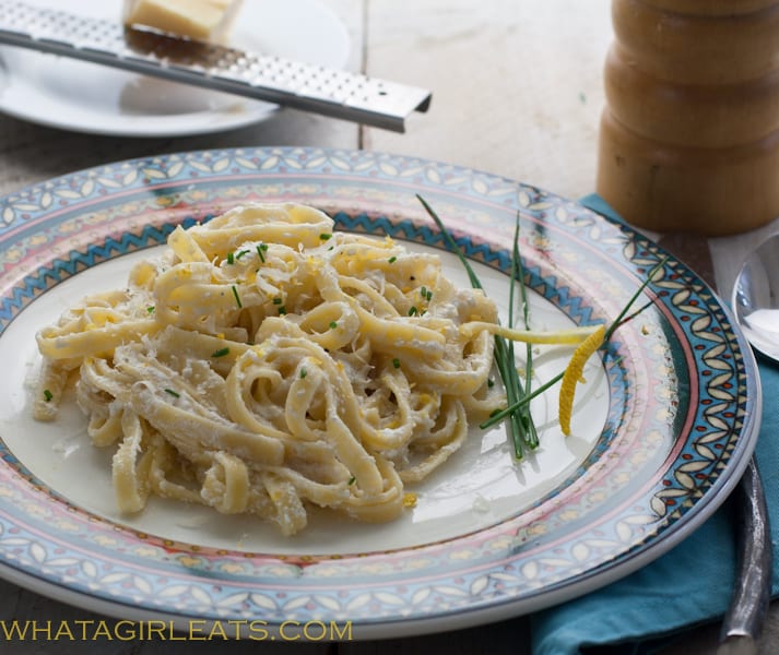 Fettucine on a plate with cheese being grated on top.