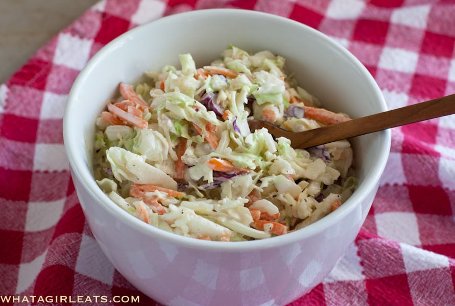 Creamy cole slaw in a white bowl with a fork in it.