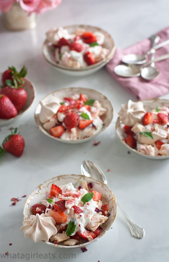 Overhead view of strawberries, cream, and meringues in a bowl.