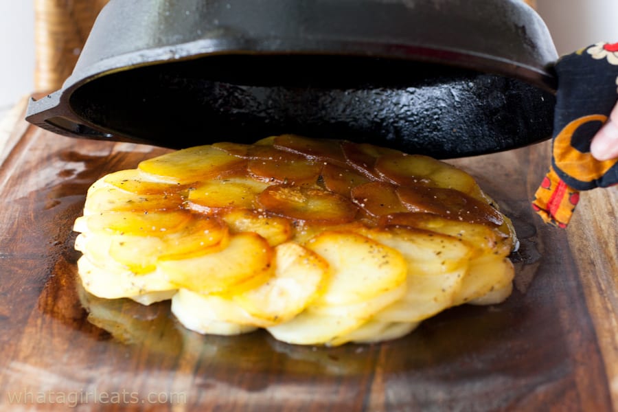 Cooked Pommes Anna coming out of a cast iron skillet turned upside down.