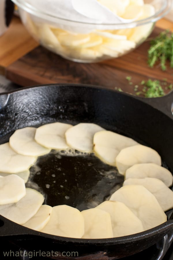 Potatoes layered in cast iron skillet.