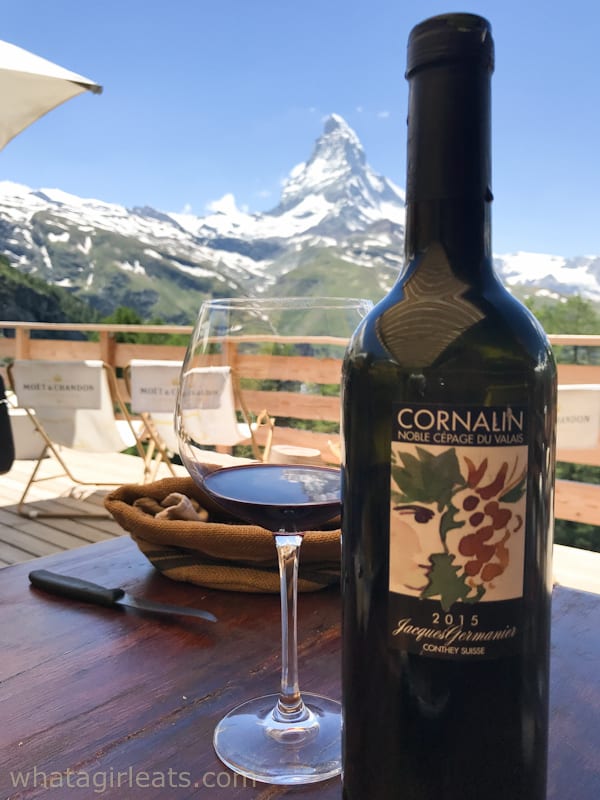 Win bottle and glass on a table with Matterhorn in the background.