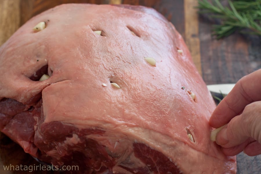 Uncooked leg of lamb studded with garlic
