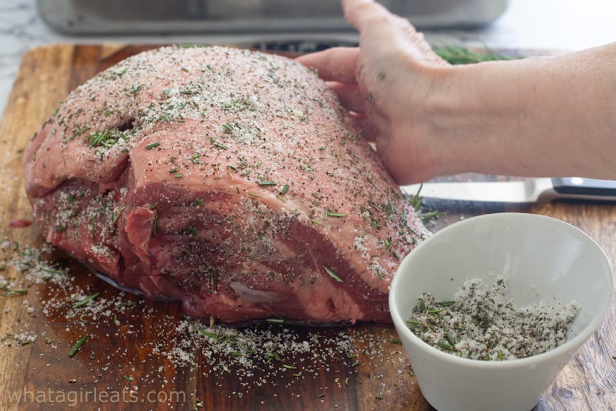 Rubbing leg of lamb with fresh herbs and spices.