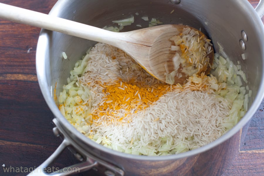 Onions, turmeric and rice in a sauce pan.