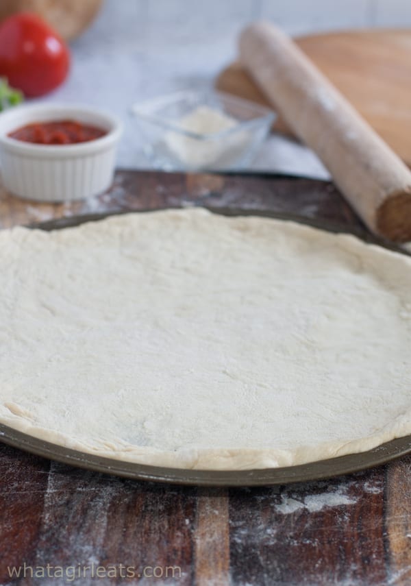 raw pizza dough on a pizza tin