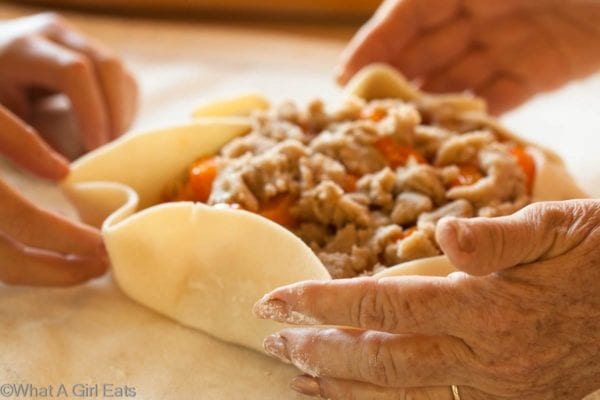 Grandmother and granddaughter hands working together on peach crostata.