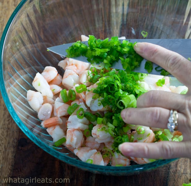 Adding herbs and onions to the bowl of shrimp