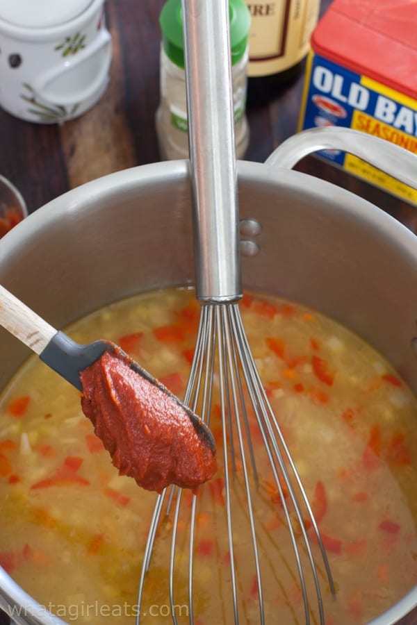 Tomato paste being whisked into a pot of soup.