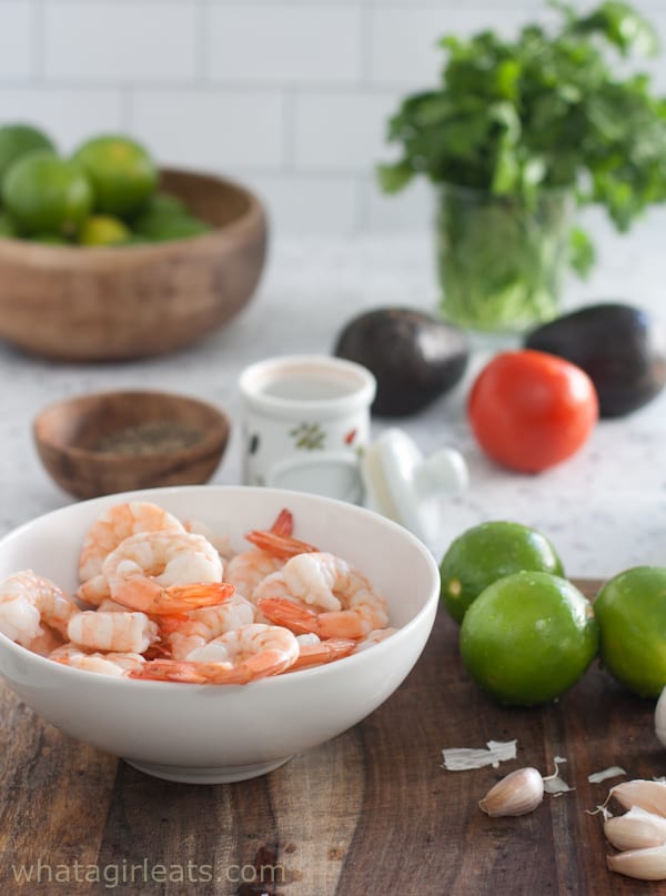 Shrimp, lime, and other ingredients for shrimp cocktail on a plate.