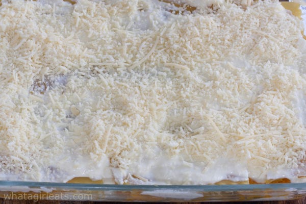 Lasagna layered in baking dish and topped with shredded mozzarella cheese.