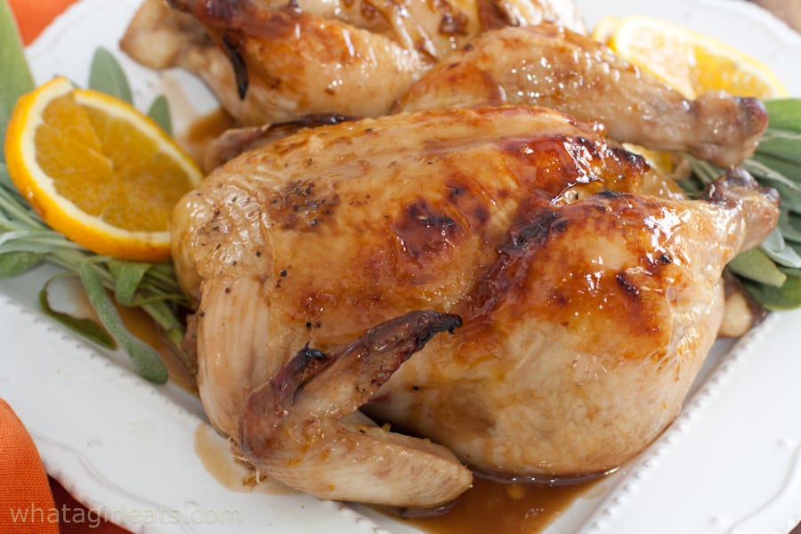 Close up of Cornish hens on a white plate garnished with lemons.