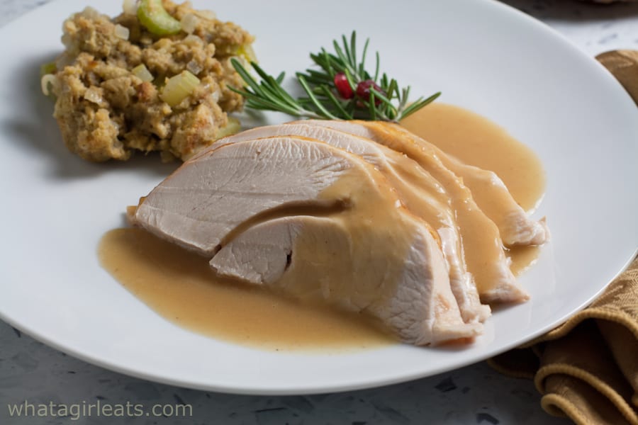 Slices of turkey on plate with gravy and stuffing.