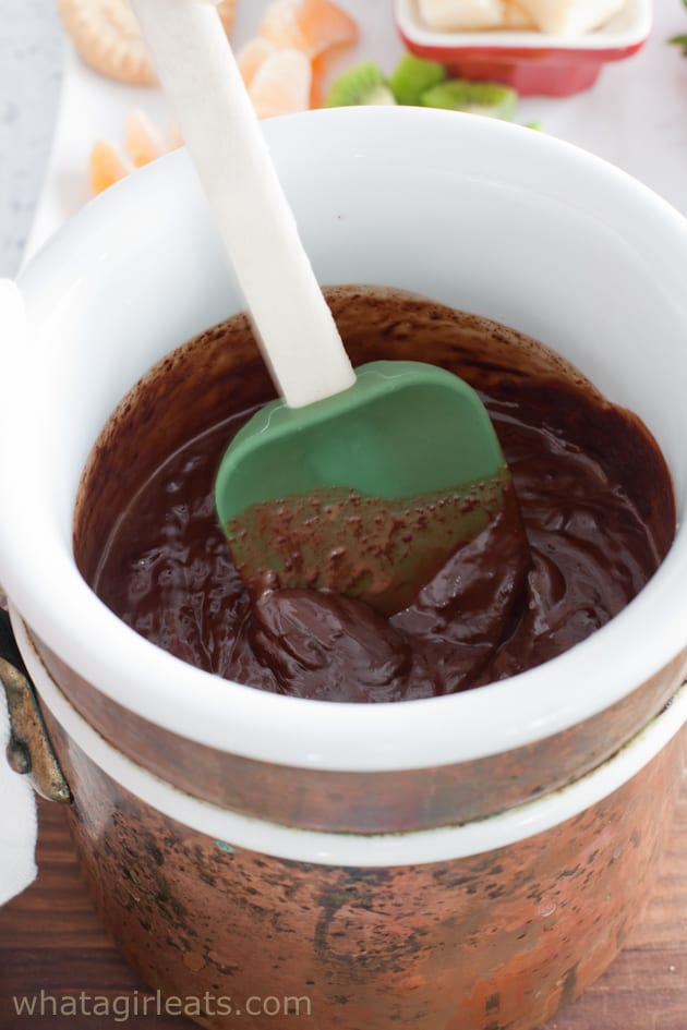 Melted chocolate fondue being stirred with a spatula. 