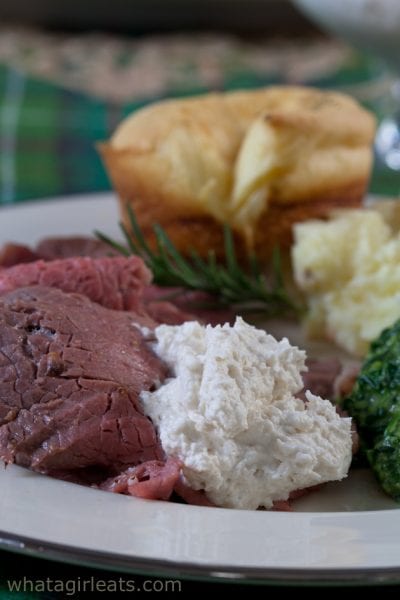 Prime rib on a plate with horseradish sauce on top.