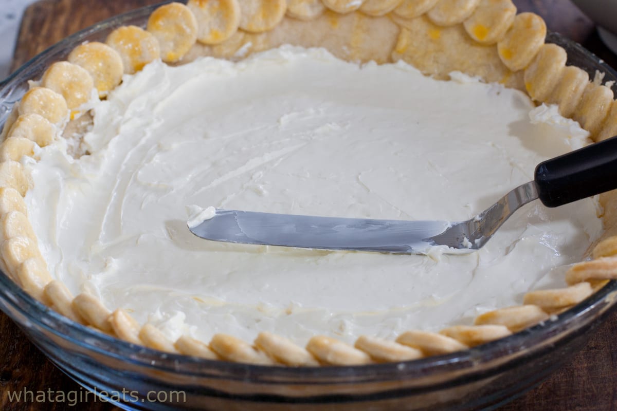 Spreading cream cheese filling inside the pie crust.
