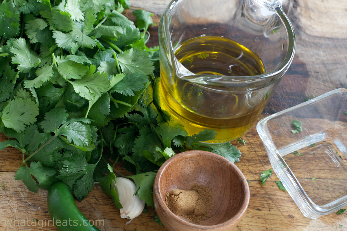Cilantro, olive oil, and spices on a table.