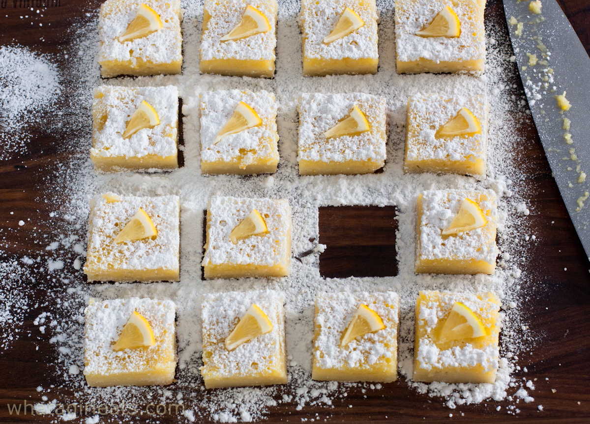 Lemon bars on cutting board, dusted with confectioners sugar.
