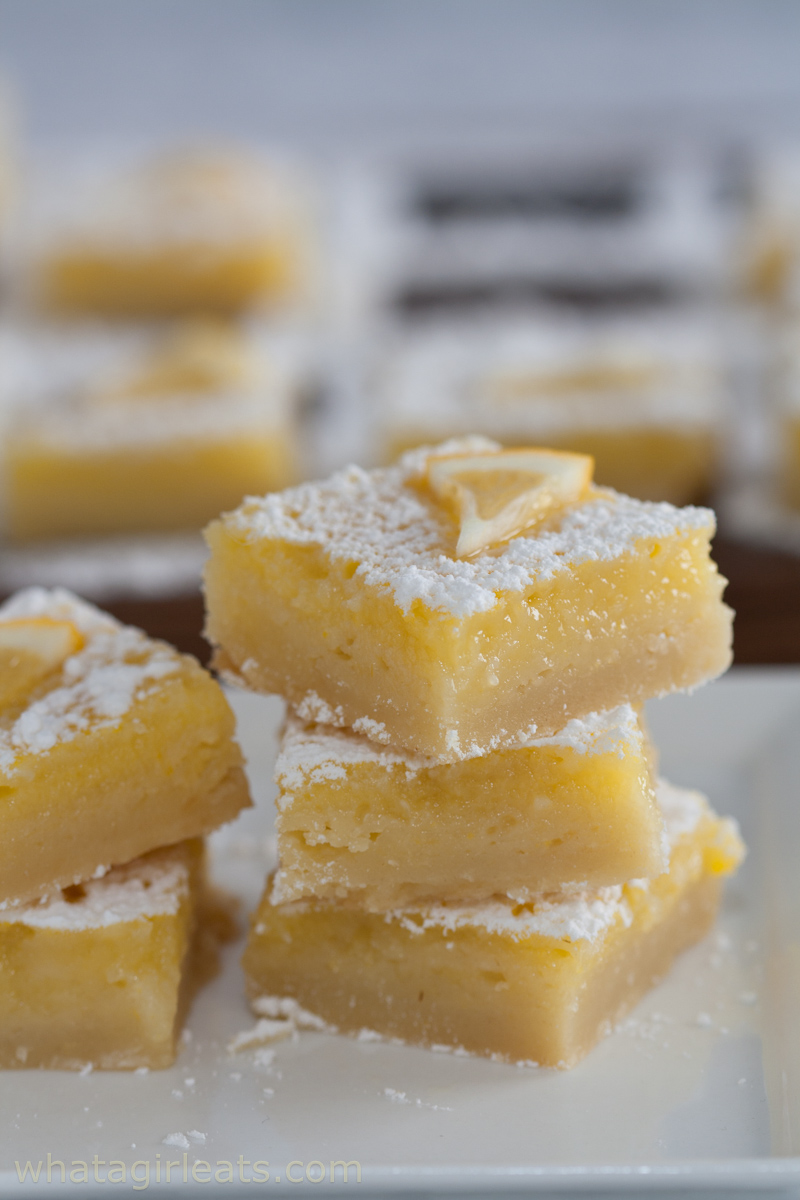 Close up of lemon bars stacked on a plate.