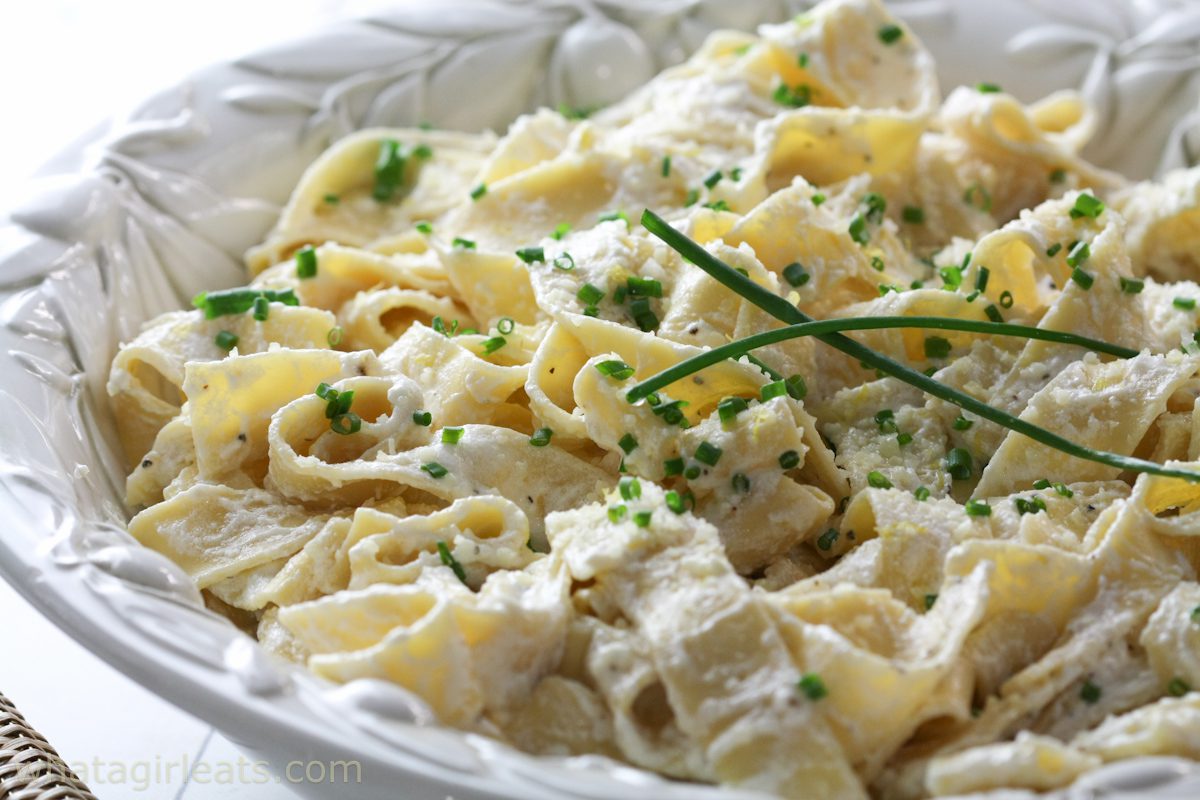 Greek yogurt pasta garnished with chives in a white bowl.
