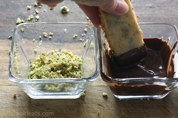 dipping one end of pistachio shortbread in chocolate. 