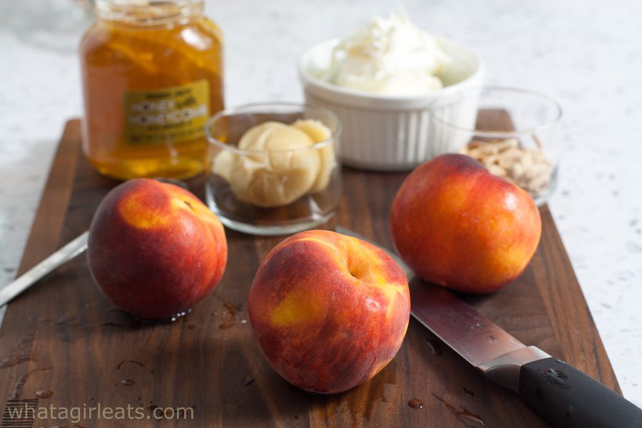Peaches on a cutting board with other ingredients in the background.