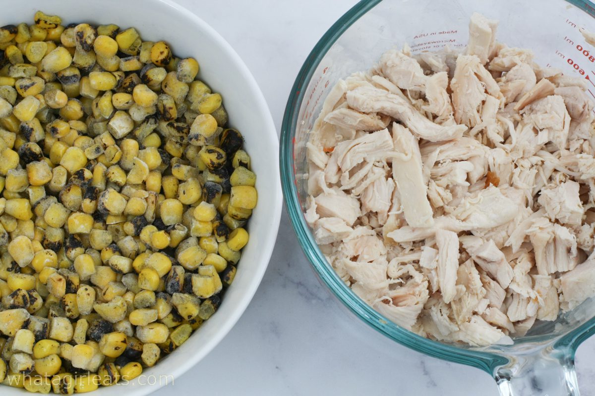 Corn and shredded chicken in glass bowls.