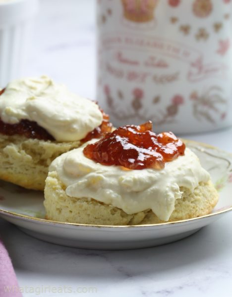 Clotted cream on scone with raspberry jam.