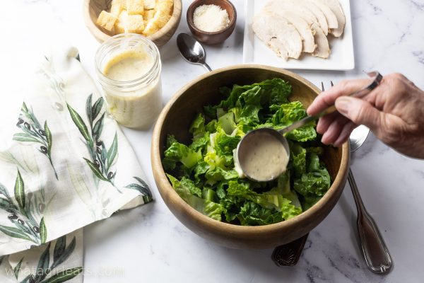tossing caesar salad with dressing.