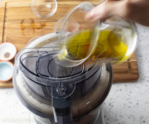 adding olive oil to food processor.