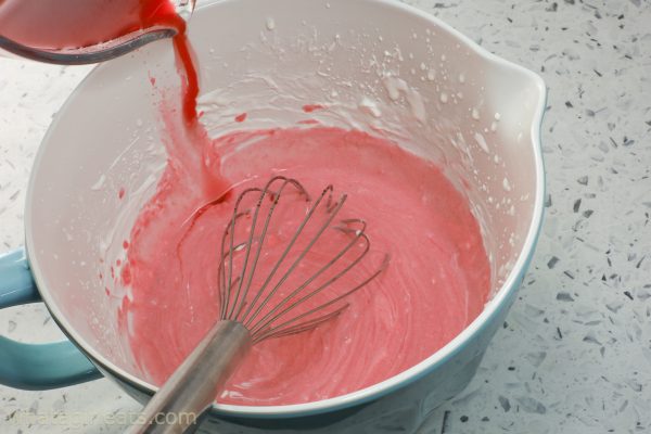 adding raspberry sauce to whipped cream.