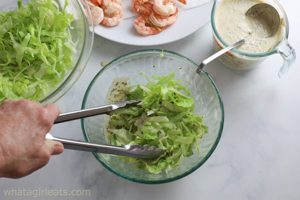 tossing lettuce in remoulade sauce.