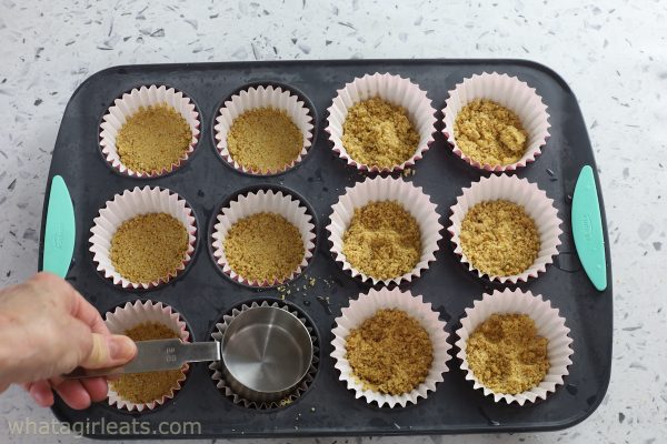 graham cracker crumbs in muffin tin.