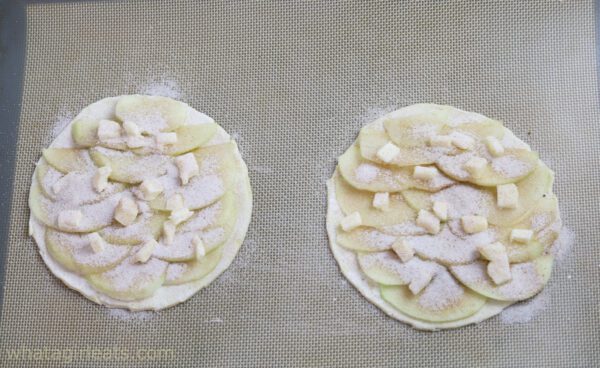 dotting apple tarts with butter and cinnamon sugar.
