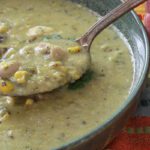 chicken soup with green chilies on spoon.