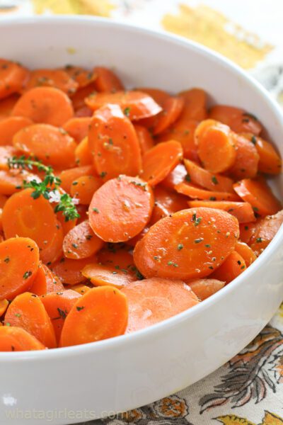 maple glazed carrots vertical shot in white bowl.