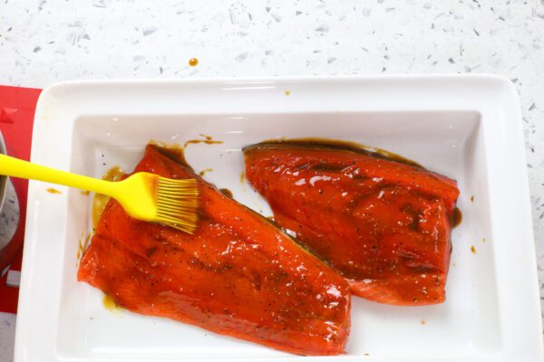 brushing glaze on honey mustard salmon.